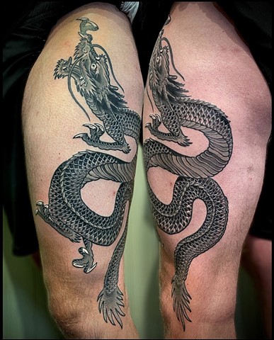 A black and grey, traditional Japanese dragon, snaking up the thigh