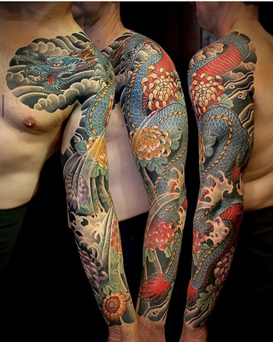 A blue traditional Japanese dragon sleeve from chest to wrist, accompanied by colorful chrysanthemum flowers