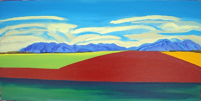 A large brown/red field in front of blue mountains