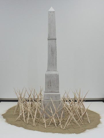 Stylized monument based on local Confederate memorial, surrounded by grasses dipped in porcelain, burned away, and assembled into caltrops, resting on a bed of ashes.