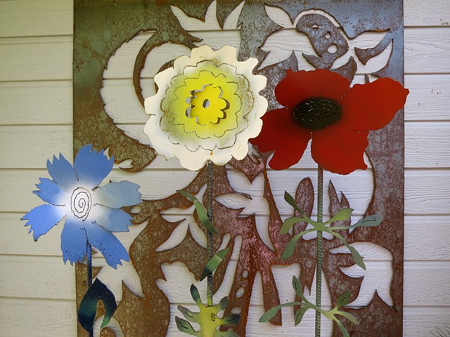 3 steel garden flowers against the backdrop of a steel screen