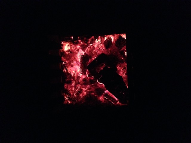 The tins of wood (now charcoal) are left in the coals of the fire.  As the fire dies down, the tins are left to cool before removing.