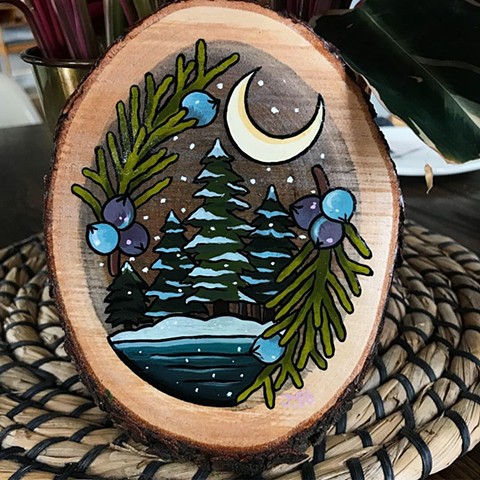 Winter nature scene with trees and snow surrounded by juniper berries in a tattoo style on wood