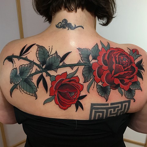 Red rose cover up traditional tattoo in a bold style on a woman’s back made in Toronto Ontario Canada 