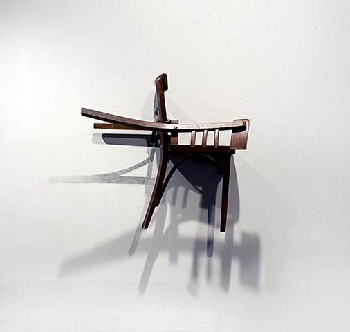 This is a sculpture comprised of a reconfigured found chair and graphite wall drawing of its cast shadows.