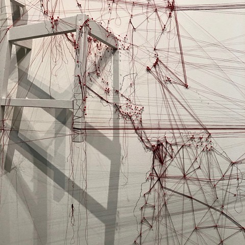 Detail of an installation about migrations completed at the San Francisco Arts Commission Gallery.  A large map of the world was drawn on the wall in graphite, map pins and red thread trace the paths of current major migrations. 