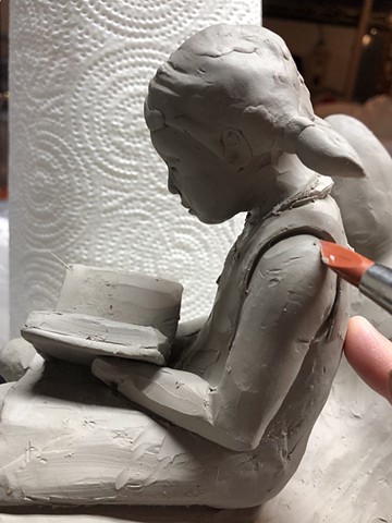 Carving out details on wet clay.