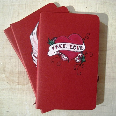 traditional tattoo design of a red heart with true love written across it, on an original red Moleskine Cahier notebook. By Brighton painter Linda Boucher