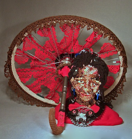 Mixed media sculpture of African girl in buttons and crochet with Bicycle wheel by Marie Bergstedt