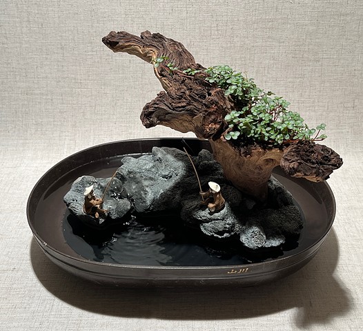 Tabletop fountain with driftwood, miniature fisherman figures, and live plants
