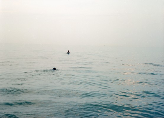 Lake Michigan on an overcast day with a dog and girl swimming in the vast lake photographed by Lucy Mueller