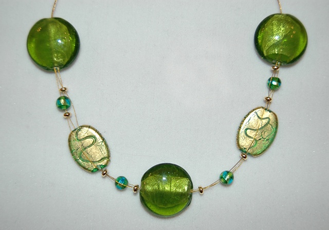 Triple strand interwove necklace comprised of incised gold foil over green glass beads  accented with large puff-coin-shaped murano style green glass beads