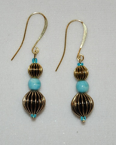 Earrings of Corrugated goldtone metal beads surrounding aqua ceramic bead 