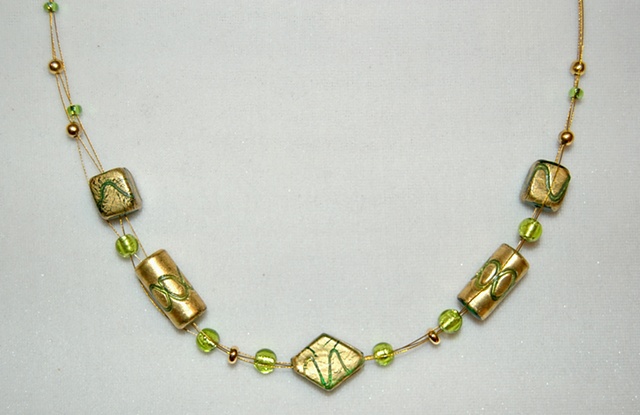 Triple strand necklace of incised gold foil over green glass beads, diamond-shaped,  tube-shaped, and square accented with green murano style glass beads