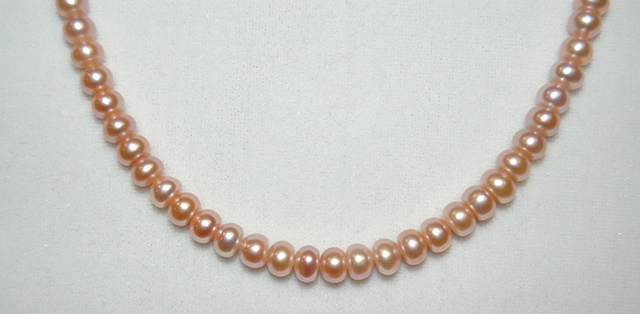 Single strand necklace of button-shaped freshwater pearls in a soft peach-tone pastel with Sterling silver clasp