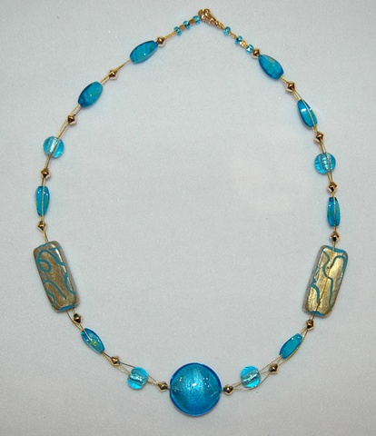 Triple strand interwove necklace comprised of incised 22k gold leaf over aqua glass beads accented with aqua faceted glass beads and round aqua murano style glass beads