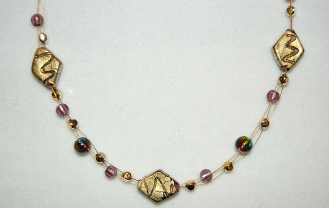 Interwove triple strand necklace of 22K Gold leaf over amethyst color glass beads and murano style amethyst beads