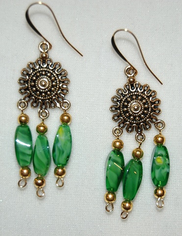 Three faceted tube-shaped swirled green glass beads accented with gold tone metal spacers dangling from central gold tone metal starburst shape 