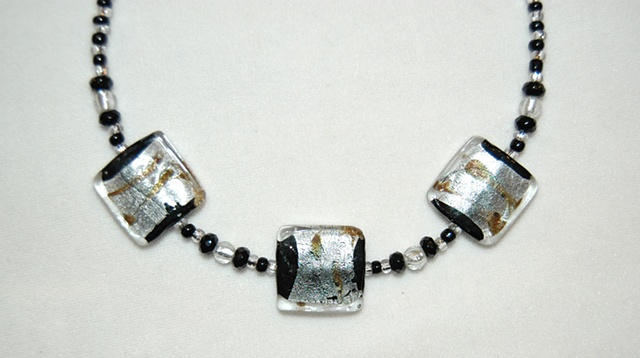 Choker length Necklace of large square Murano style glass bead of silver and gold foil over Black glass accented with small round Murano style silver-colored glass beads, black faceted crystal beads 