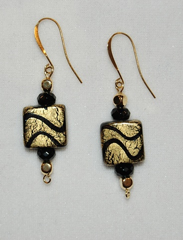 Earrings crafted from incised gold foil over black glass beads with faceted rondell-shaped black crystal beads