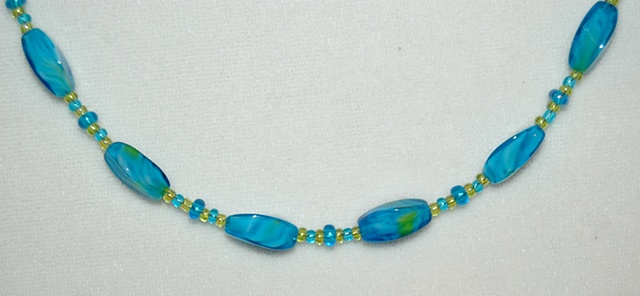 Faceted tube-shaped aqua glass beads with swirls of green accented with aqua and green glass seed beads