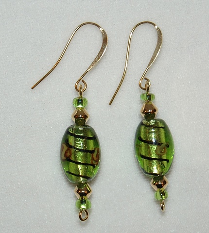 Earrings of foil interior Green lampwork glass bead with design of black swirls and rosettes accented with goldtone cone-shaped spacers and green glass seed beads 