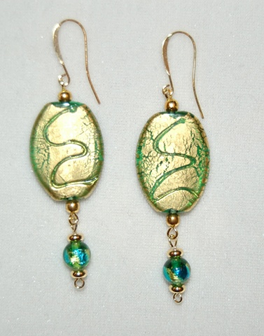 Incised goil foil over oval-shaped green glass bead accented with gold plated beads and a dangling extension of a murano style glass bead 