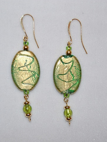 Earrings of incised gold foil over green glass bead, oval in shape accented with dangling extension of green murano style glass bead
