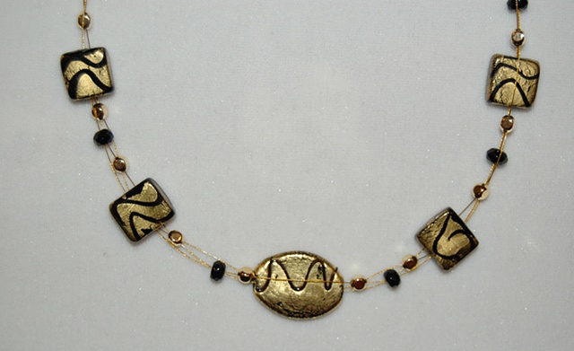 Triple strand Necklace of interwoven Incised gold foil over black glass beads, oval and square in shape, accented with faceted rondell-shaped black crystal beads 