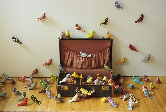 Installation of birds flying out of a suitcase