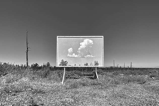 A black and white image of a billboard with a cloud placed in the high desert