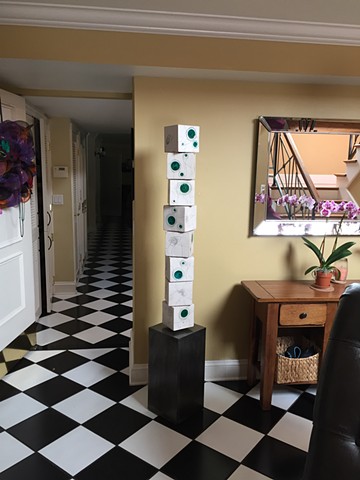 Green totem installed in a room with checkerboard floors; an orchid nearby
