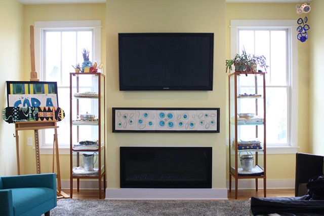 Wall piece with blue glass, mounted in a living room between the TV and the fireplace