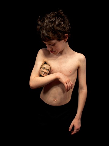 Digital C-print of a young boy with a small sculpted head under his arm