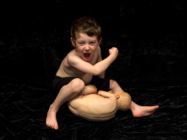 Digital C-Print of a boy in an aggressive pose over a sculpted baby