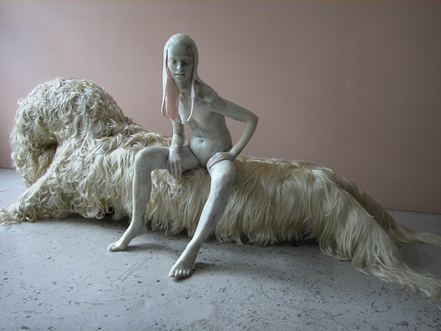 Figure modeled in microcrystalline wax sitting on a chaise upholstered in synthetic human hair