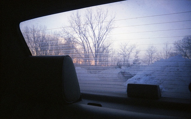 color photograph of sunset and snow through the back window of a car by iris grimm