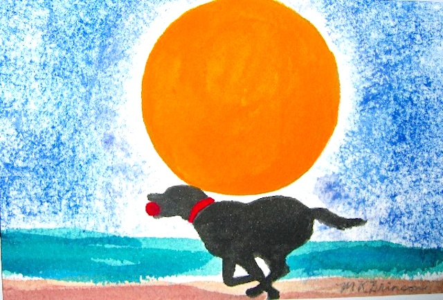 A black lab runs with a red ball on the beach in front of a big orange sun at sunset.