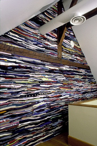 Art installation of wall of folded used clothes in textile museum