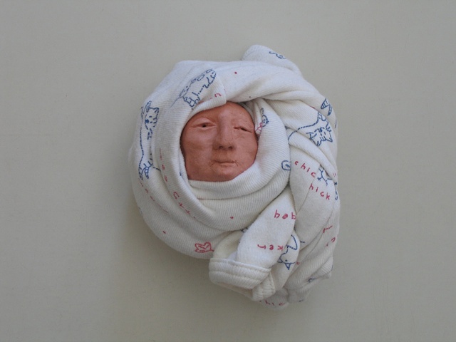 Individually modeled, walnut-sized clay heads, wrapped in baby sleepers and arranged on gallery floor with rain forest photomural 