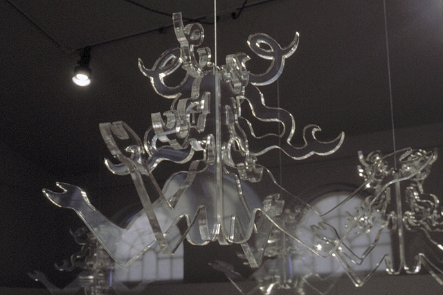 Art installation of eight figurative revolving clear plexiglas chandeliers 