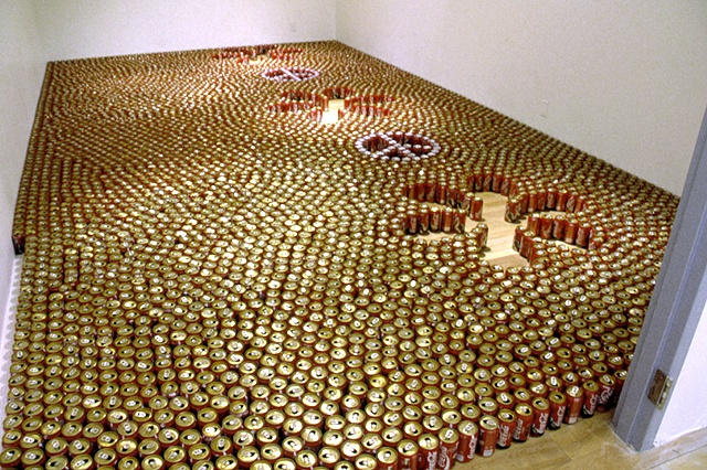 empty coke cans arranged on the floor in a "peace and love" pattern