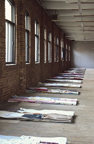 Art installation of bed-forms made of folded used clothes 