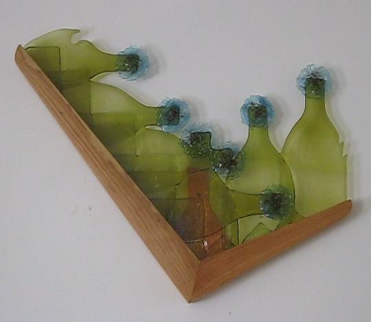 Bottle glass, fused swarf, red frit, wood.  A wall piece.