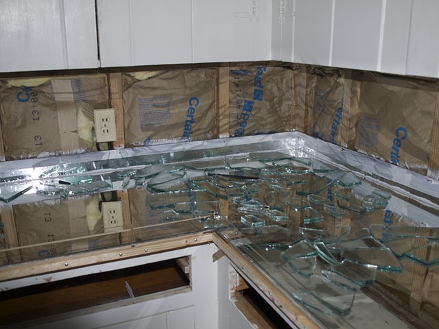 Back splash is removed and insulation was added. Wood is sealed and taped up the wall and Sherry's closet door mirrors are laid in the mold first and then broken mirror is laid on that. This will give the appearance of light coming up through the counter 