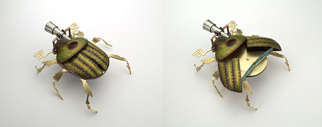 fabricated metal beetle with wings that open to reveal a folded metal element