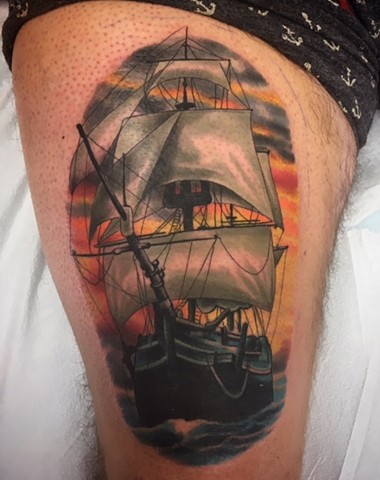 Colour pirate ship tattoo on upper thigh by tattoo artist Brett Schwindt at Strange World Tattoo in Calgary, Alberta