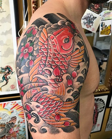 koi fish tattoo on upper arm in colour Strange World Tattoo Calgary Alberta Canada 