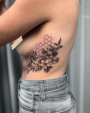 Strange world tattoo Calgary alberta Canada Valeriia moss.tattoo geometric honeycomb hexagons resting behind a floral bouquet with leaves all in black and grey centered a bee in colour pollinating a flower soft black and grey sketch illustrative style fem