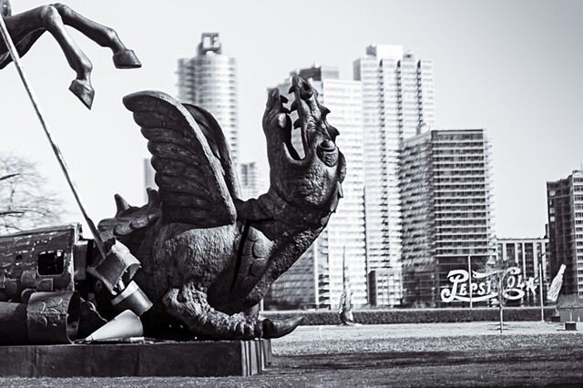 Photograph of a dragon being slain by St George on the grounds of the United Nations building with the Pepsi Cola sign and Queens in the background, by Judith Ebenstein